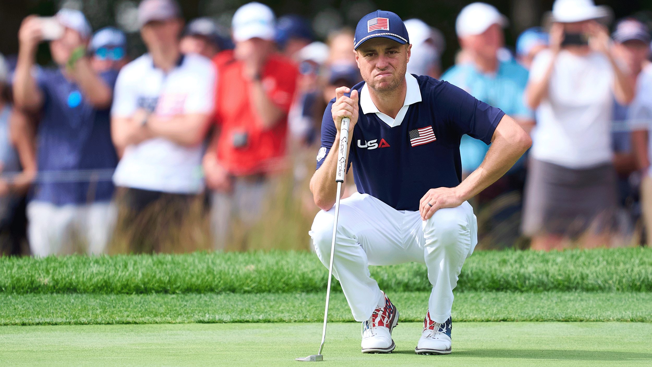 Justin Thomas crouches down behind a putt during day two of the 2025 Ryder Cup at Bethpage Black