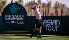 Anthony Kim hits a tee shot in front of a tee banner